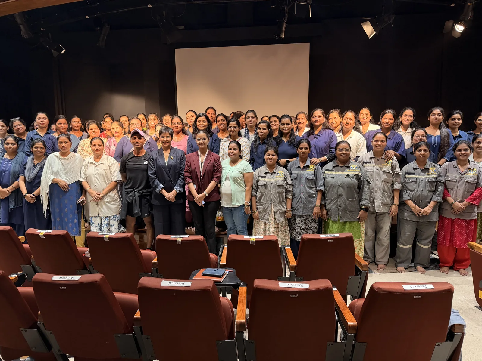 Participants standing together for a group photograph inside an auditorium.